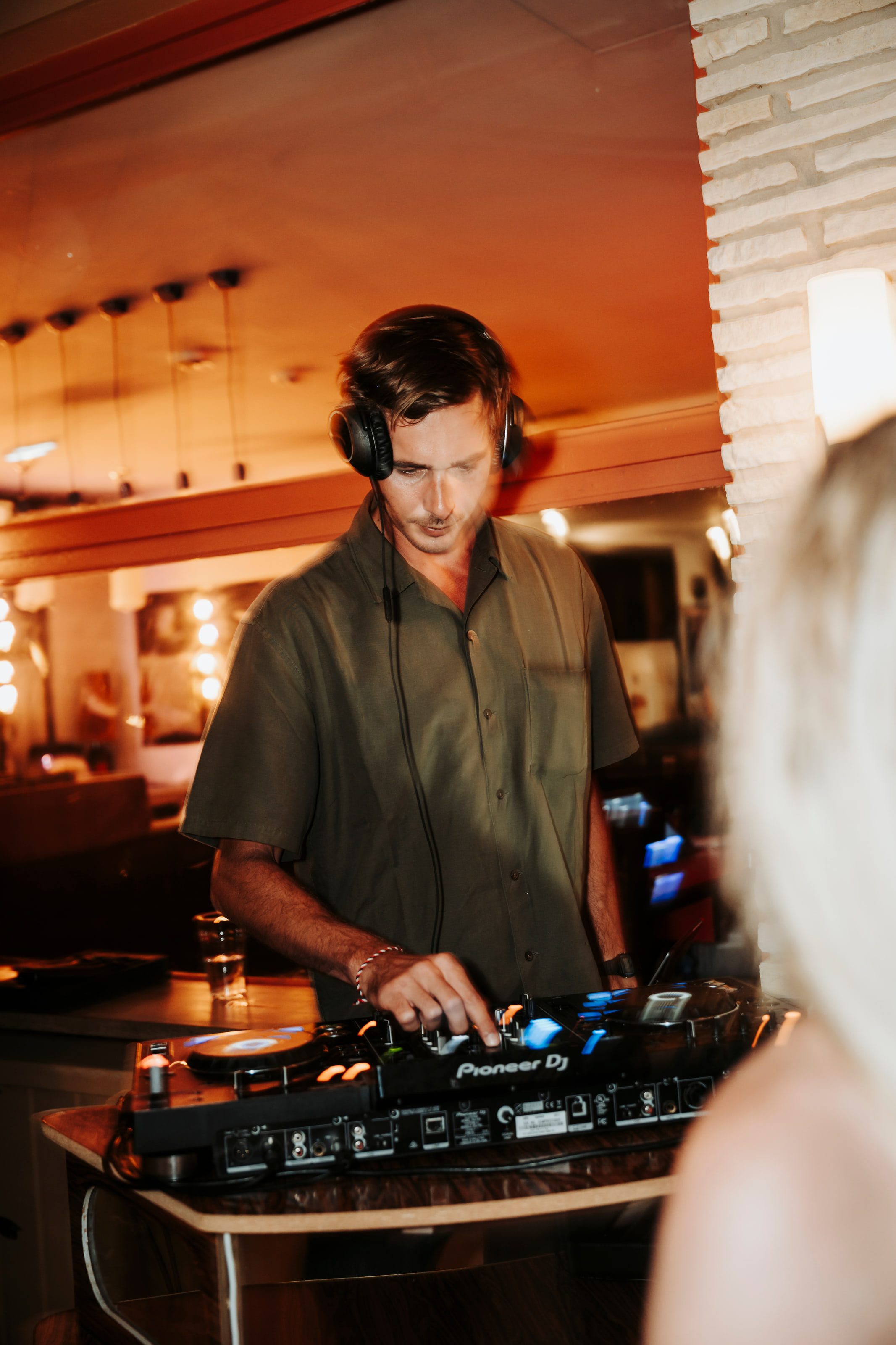 Denver behind the decks in a warm, low-lit interior.